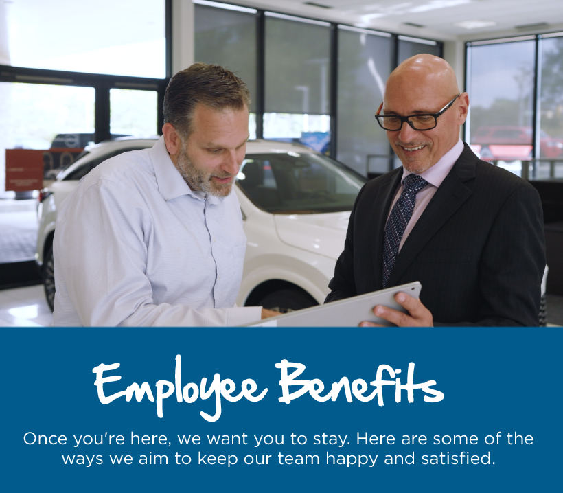Text reads, “Employee Benefits. Success is more than just car sales. We want to be a part of bettering our community together.” Above the text, two people in a showroom review information on a tablet beside a vehicle.